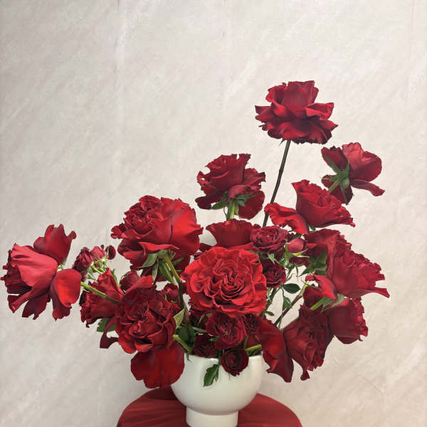 Red roses arranged in a white vase on a draped table