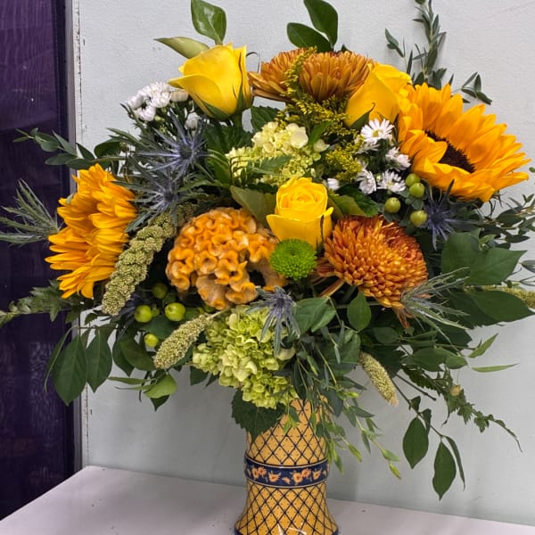 Yellow and orange floral arrangement in a patterned vase