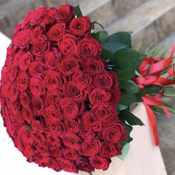 Large bouquet of red roses with green leaves and red ribbon