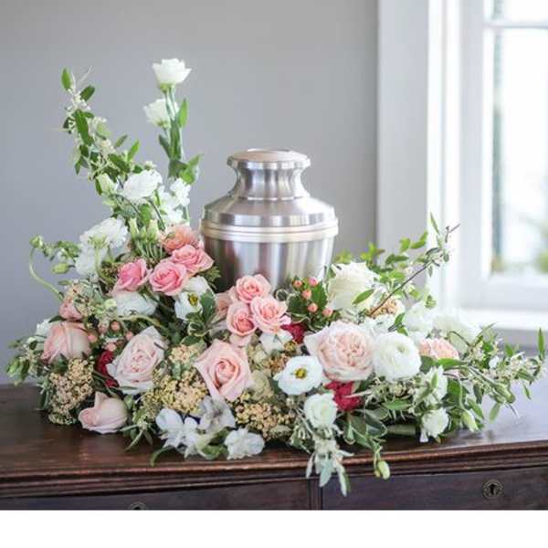 Pink and white floral arrangement around a silver urn