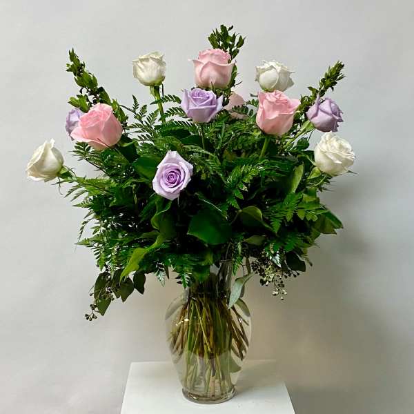 Bouquet of pink, lavender, and white roses in a clear glass vase