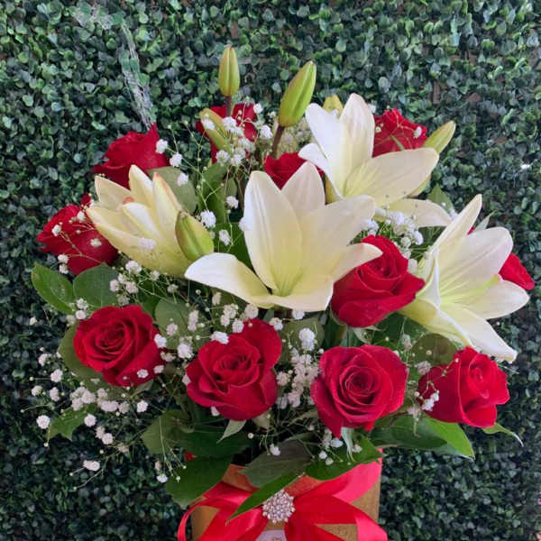 Bouquet of red roses and white lilies in a gold box with a red ribbon