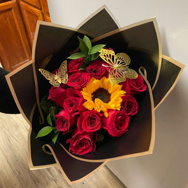 Bouquet of red roses and a sunflower in black wrapping with gold butterfly accents