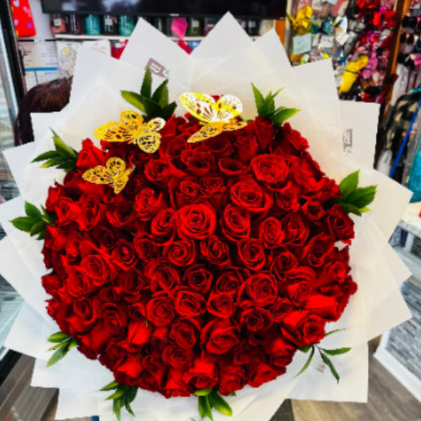 Large bouquet of red roses wrapped in white paper with yellow butterfly accents
