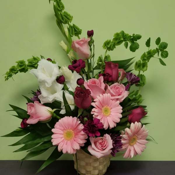 Pink and white mixed flower arrangement in a woven basket