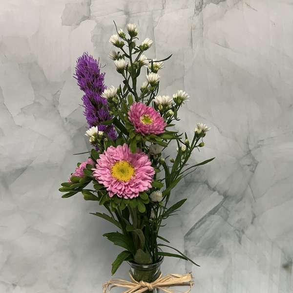 Pink and white flowers in a tall glass vase tied with raffia