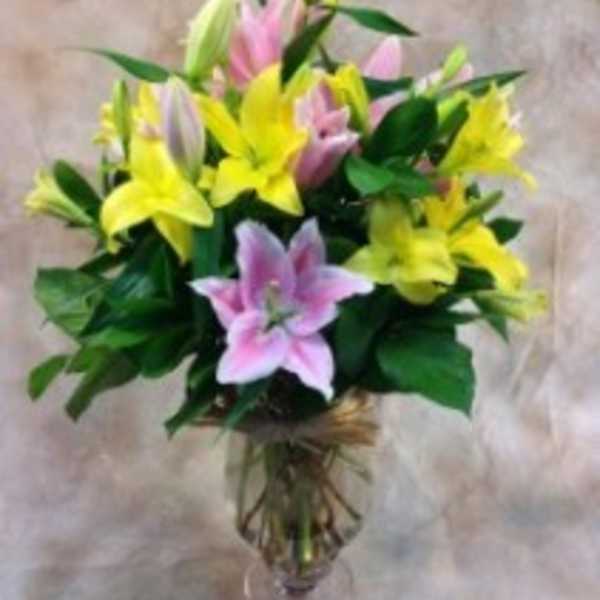 Bouquet of pink and yellow lilies in a glass vase