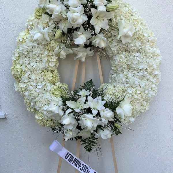 White floral funeral wreath on a wooden easel
