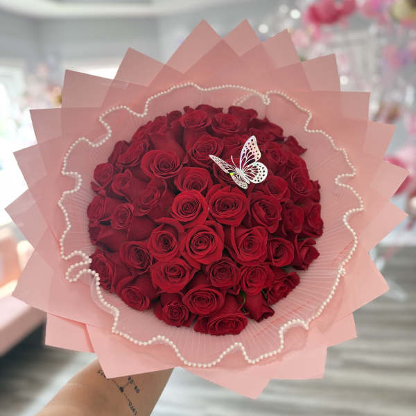 Bouquet of red roses wrapped in pink paper with a butterfly decoration