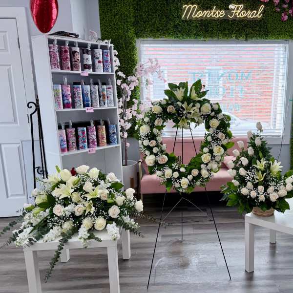 White rose and lily sympathy set with heart wreath on stand and coordinating sprays on white tables