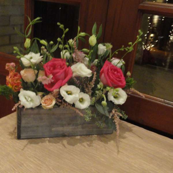 Mixed pink, white, and peach flowers arranged in a wooden box
