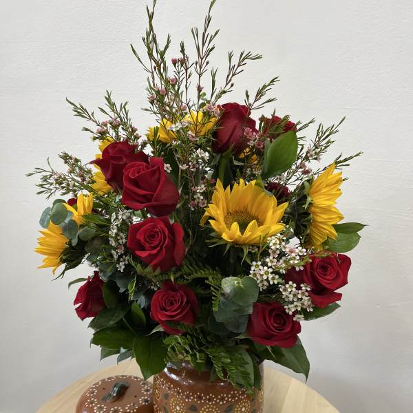 Bouquet of red roses and yellow sunflowers in a painted ceramic vase