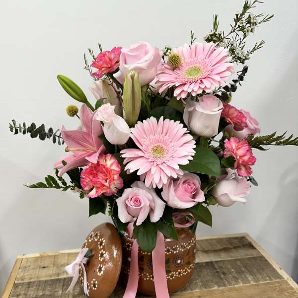 Pink bouquet with roses, gerbera daisies, lilies, and carnations in a painted pot