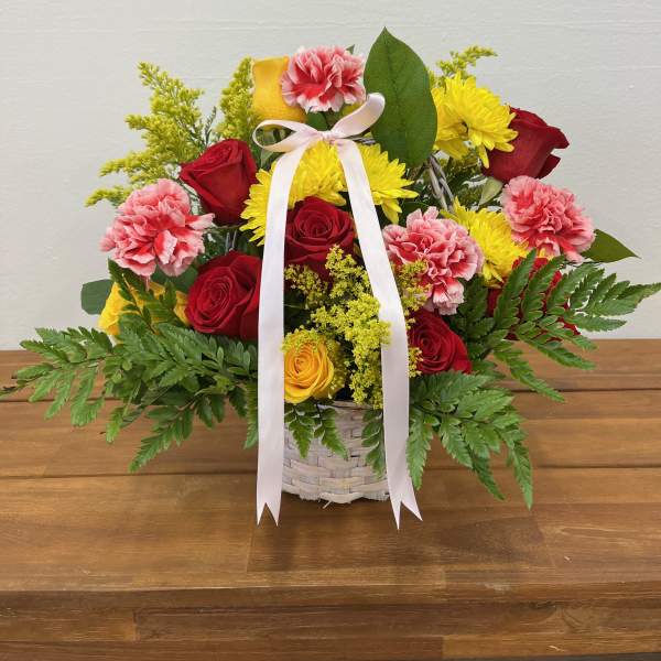Basket arrangement of red and yellow roses with pink carnations and a white ribbon