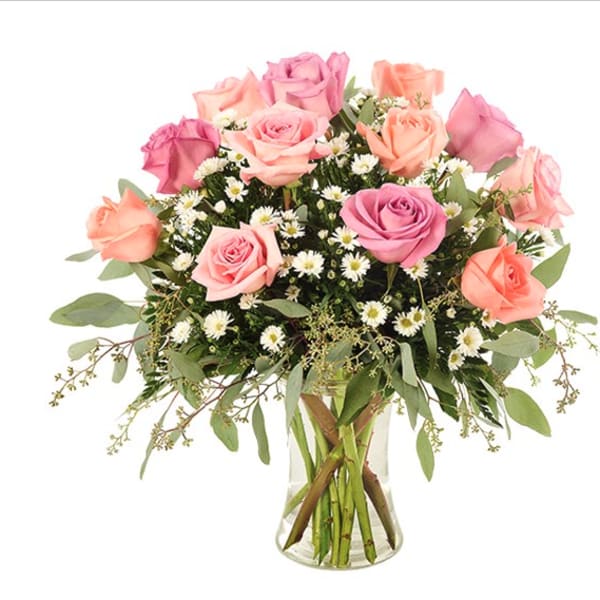 Pink and peach roses in a clear glass vase with small white filler flowers