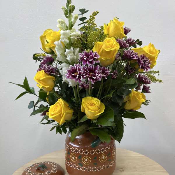 Yellow roses and purple chrysanthemums in a painted ceramic vase