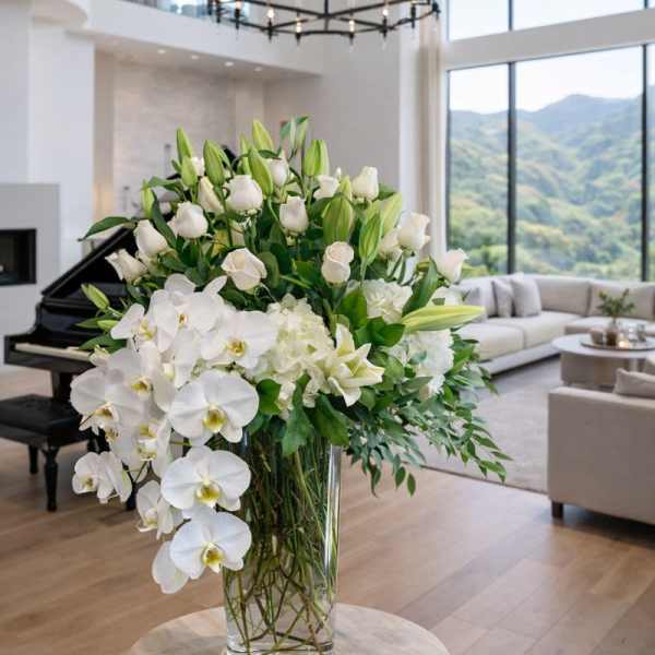 Large white floral arrangement in a clear glass vase