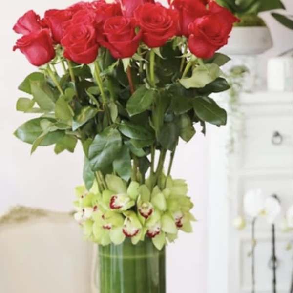 Tall vase arrangement of red roses with green orchids