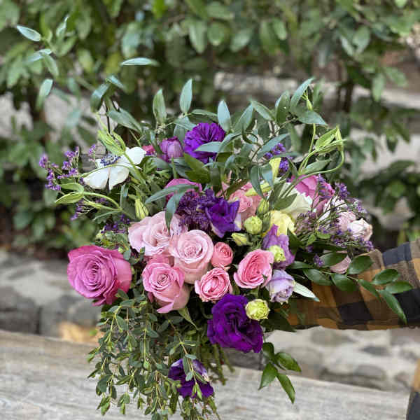Hand-tied bouquet of pink and purple roses with greenery