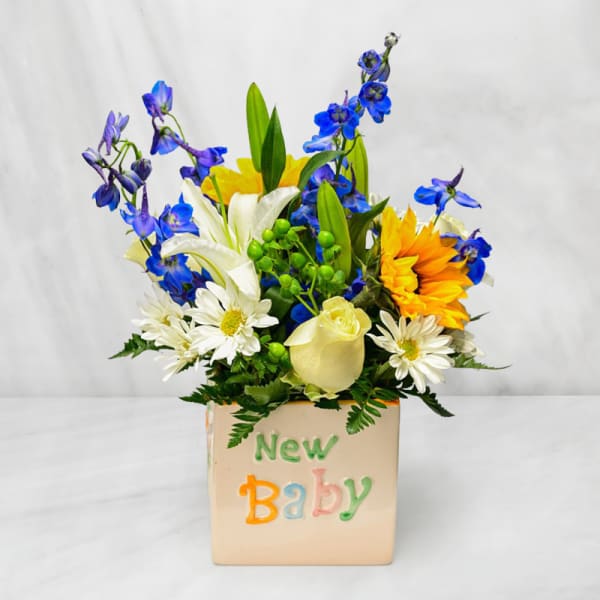 Mixed bouquet in a square vase labeled New Baby