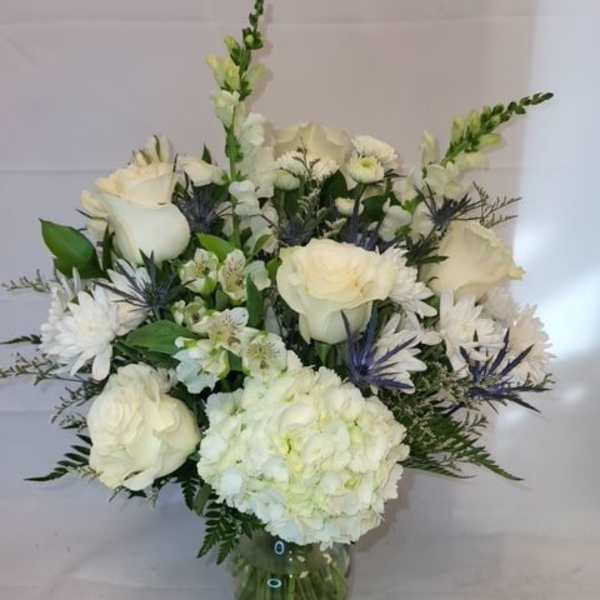 White floral bouquet in a glass vase with roses and hydrangea