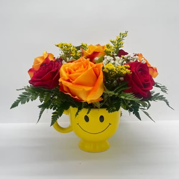 Bouquet of red and orange roses in a yellow smiley-face mug
