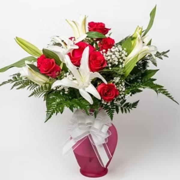 Red roses and white lilies in a pink vase with a white bow