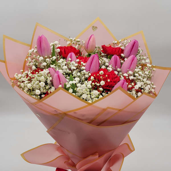 Pink tulips and red carnations in a wrapped bouquet