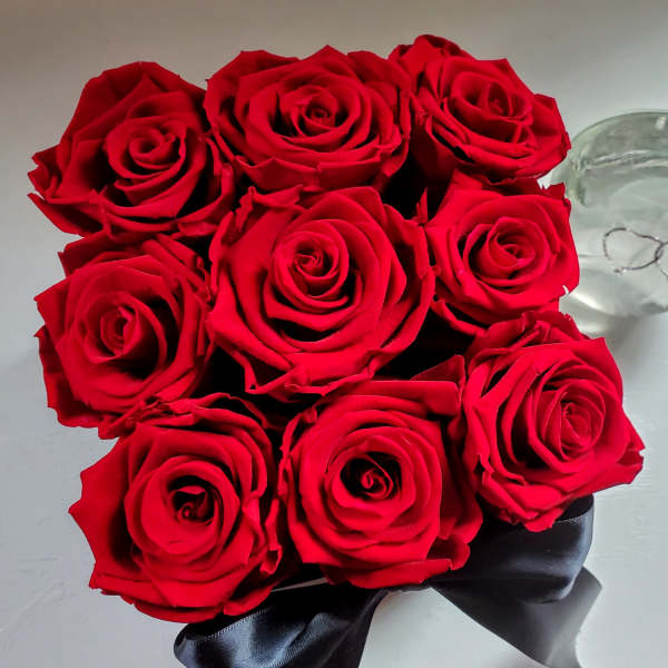 Bouquet of red roses with a black ribbon beside a clear glass bowl