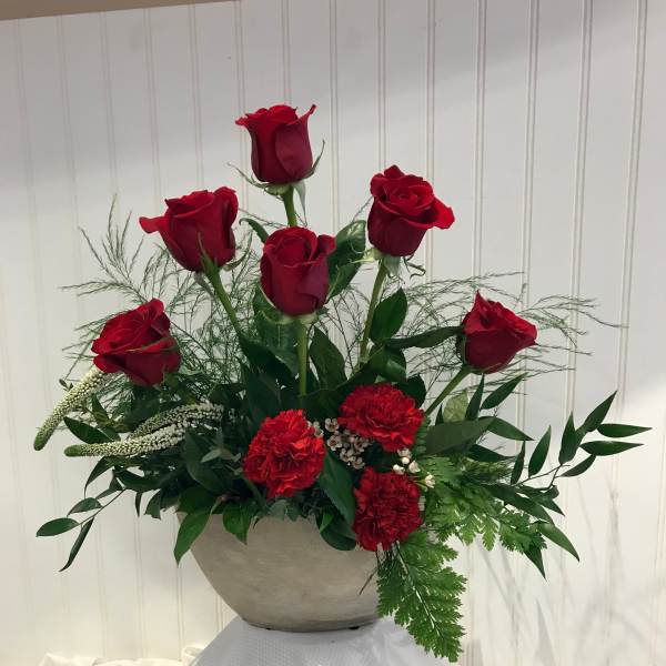 Red roses and carnations arranged in a gray bowl vase