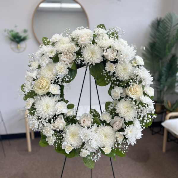 White floral wreath on a stand with roses and chrysanthemums