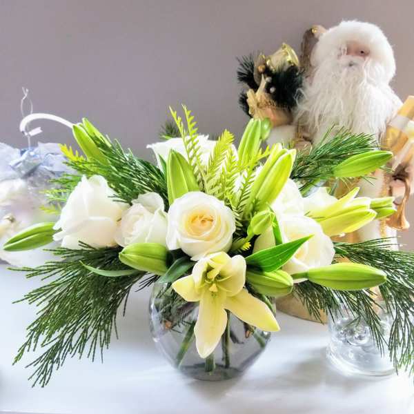 White roses and lilies arranged in a round glass vase