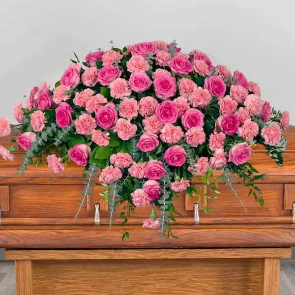 Pink roses and carnations arranged on a wooden casket