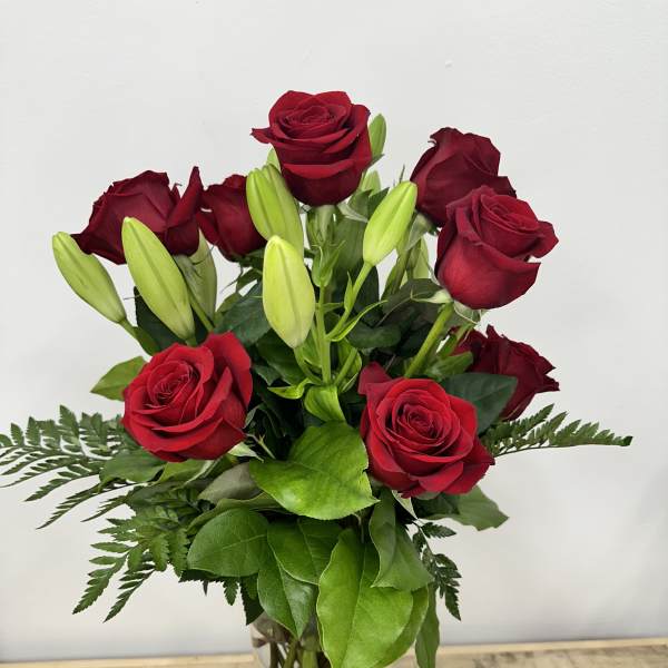 Red roses and unopened lily buds in a clear glass vase