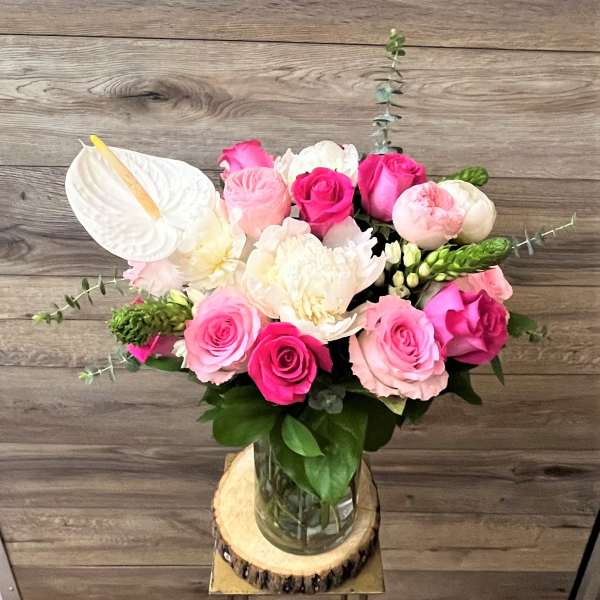 Pink and white roses with anthurium in a glass vase