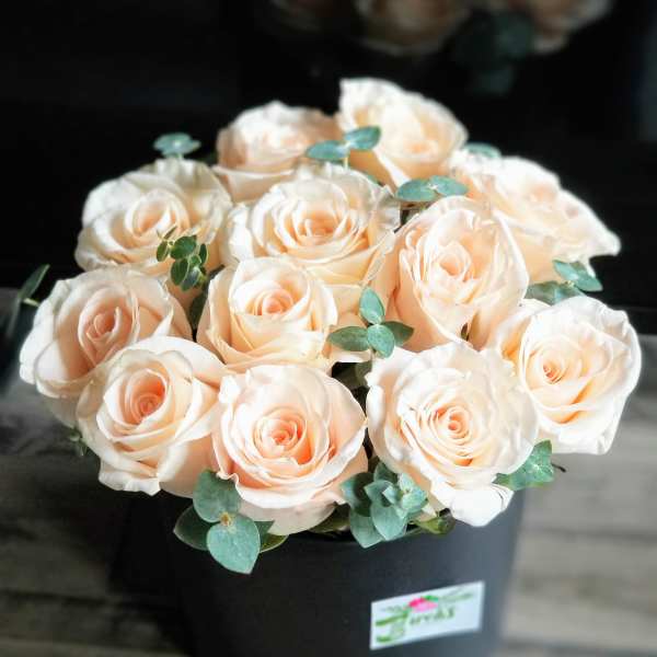 Bouquet of pale peach roses in a black box with eucalyptus