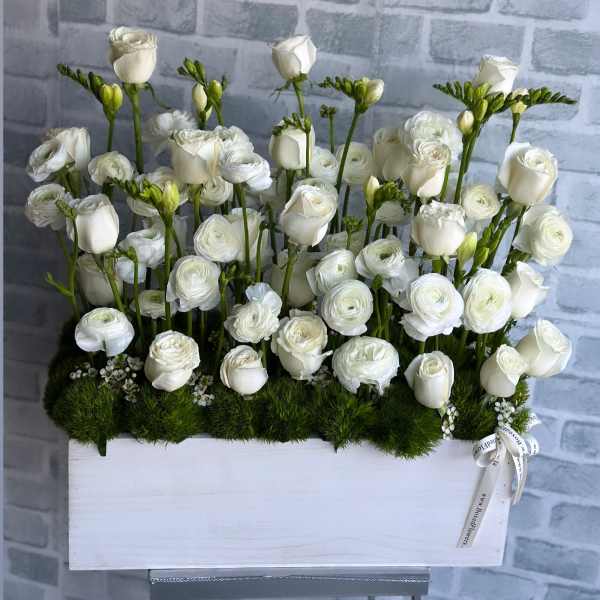 White roses and ranunculus arranged in a white box