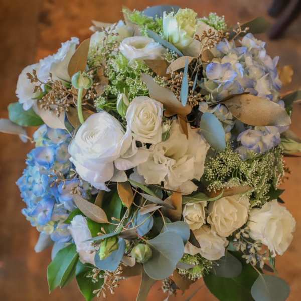 Bouquet of white and pale blue flowers with eucalyptus and gold-toned foliage