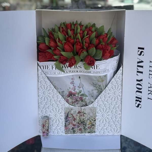 Boxed bouquet of red tulips with green leaves