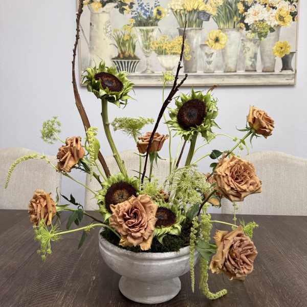 Arrangement of sunflowers and copper roses in a gray pedestal bowl