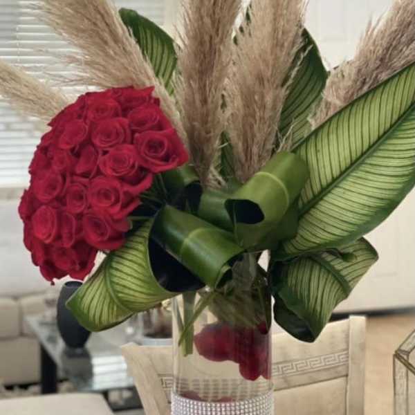 Red rose bouquet with pampas grass in a clear vase