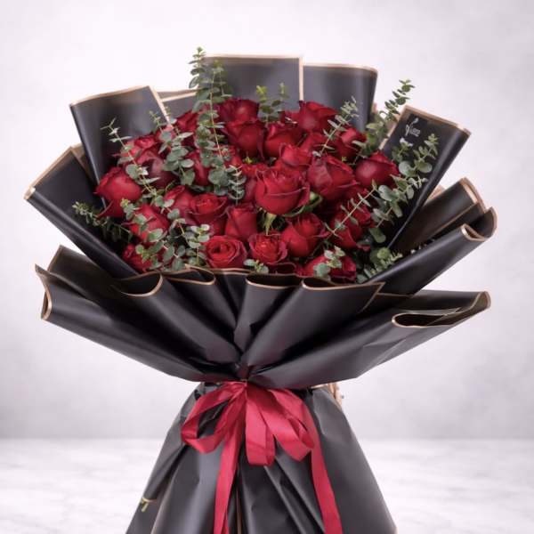 Bouquet of red roses wrapped in black paper with a red ribbon