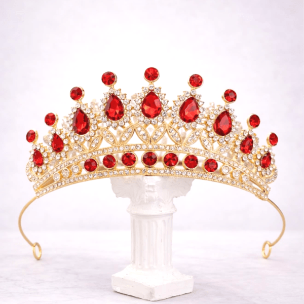 Gold tiara with red gemstones on a white stand