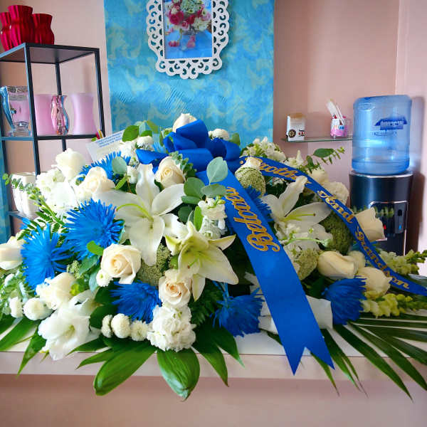 Large white and blue floral arrangement with ribbon on a table