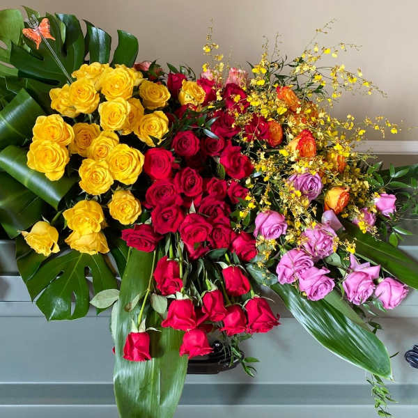 Large arrangement of multicolored roses with tropical leaves