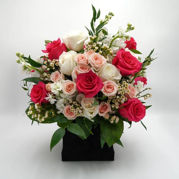 Bouquet of pink and white roses in a black box vase
