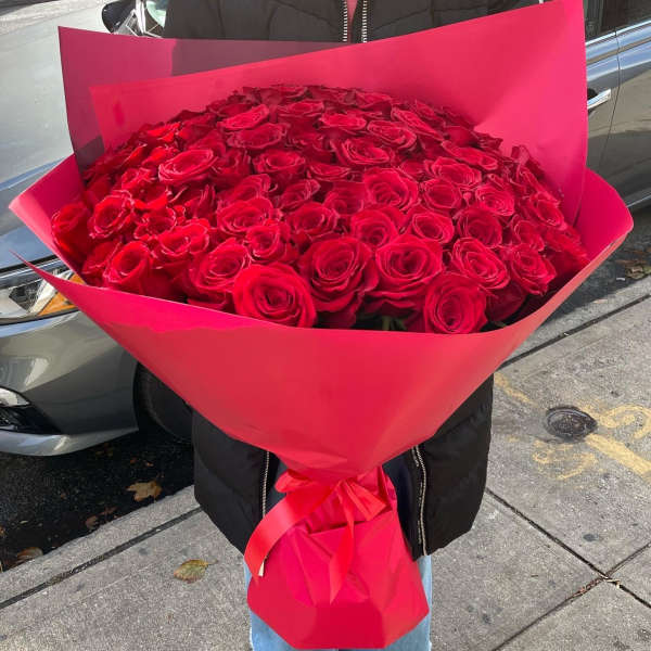 Large bouquet of red roses wrapped in bright pink paper