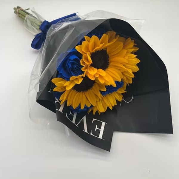 Bouquet of yellow sunflowers and blue roses wrapped in black paper