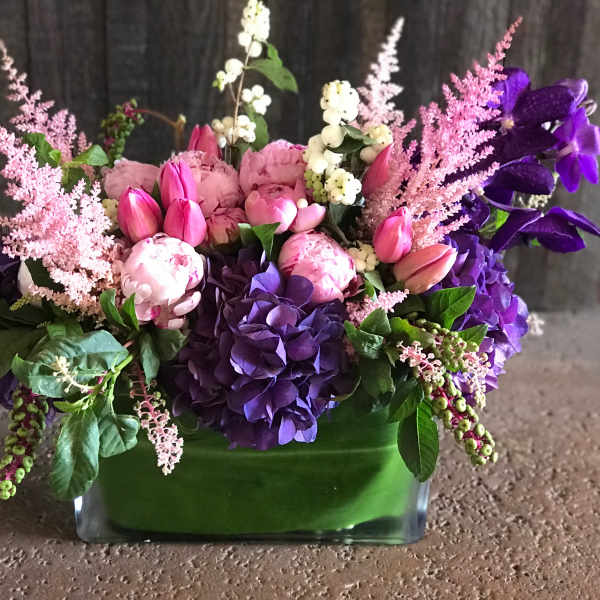 Pink and purple floral arrangement in a green glass vase