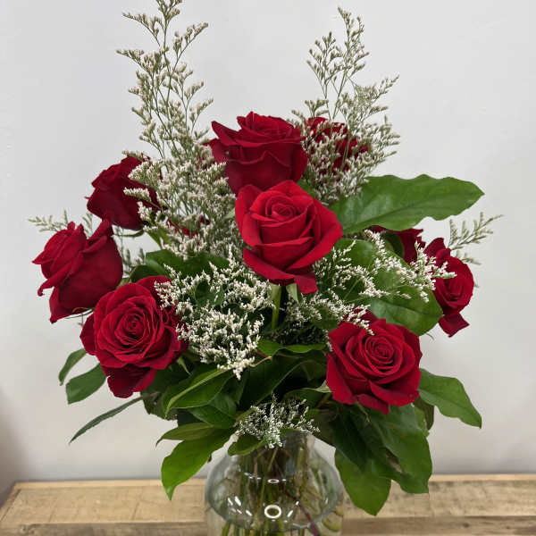 Red roses arranged in a clear glass vase with white filler flowers